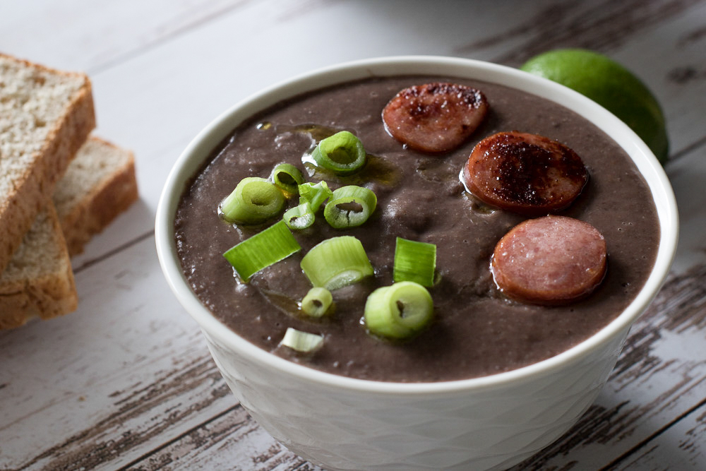 Bacon black bean soup with bread, green onions and sausage
