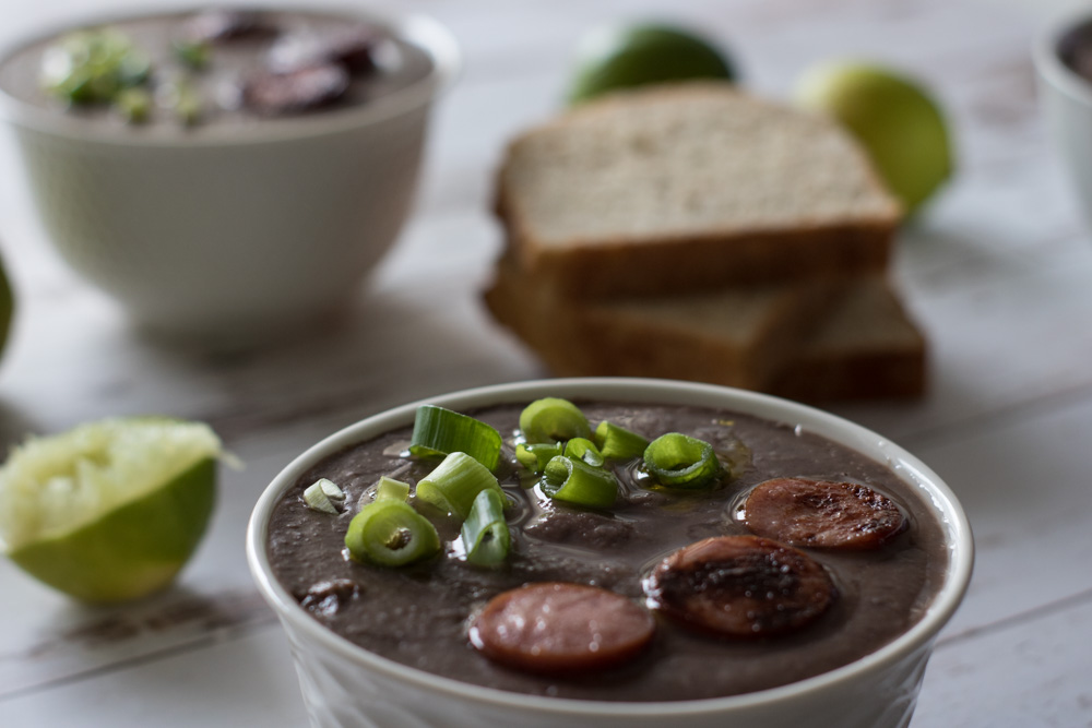 Bacon black bean soup with bread, green onions and sausage