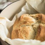 Baked beer bread inside a Dutch oven with parchment paper.
