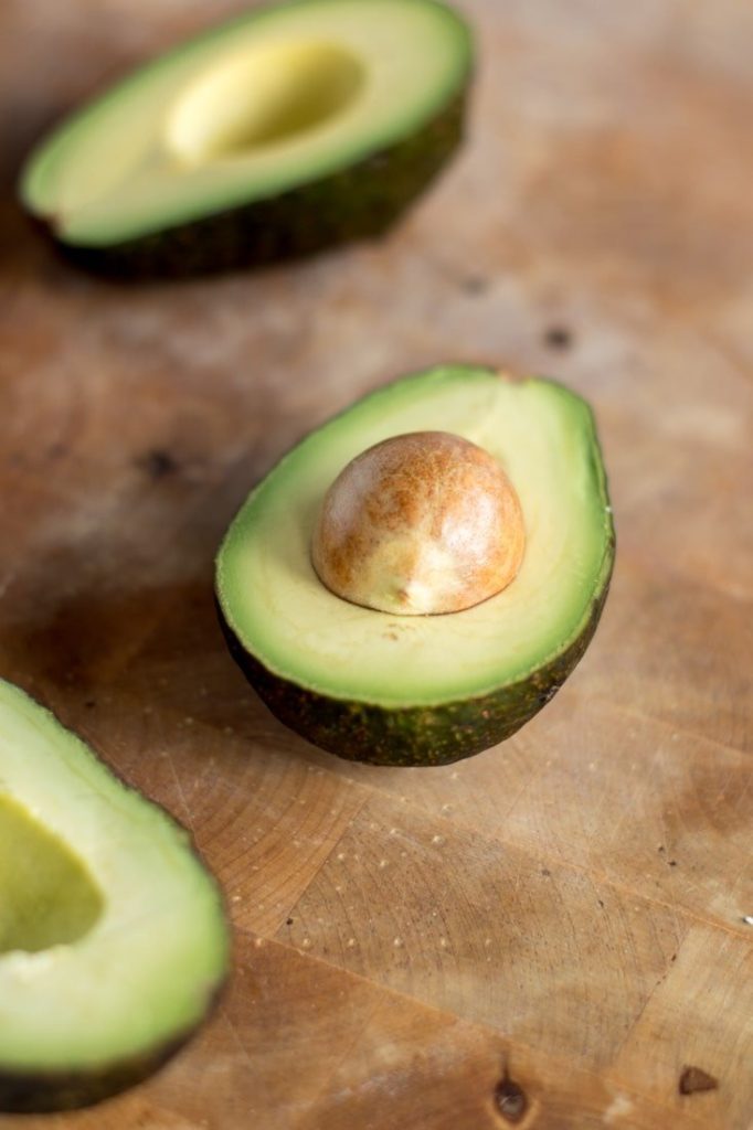 Avocado halves on a wooden board