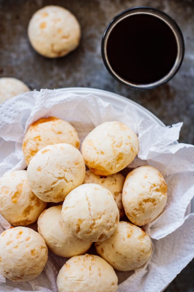 plate full of classic brazilian cheese bread with a black coffee on the side