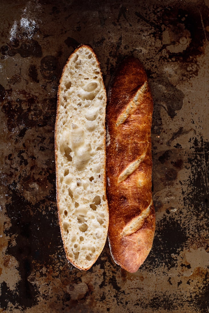 A baguette sliced in half, showing its crumb and deep golden crust.