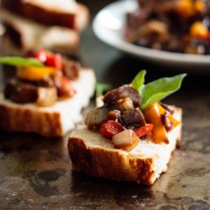 two caponata toasts with more caponata on the background