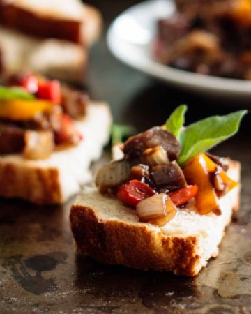 two caponata toasts with more caponata on the background