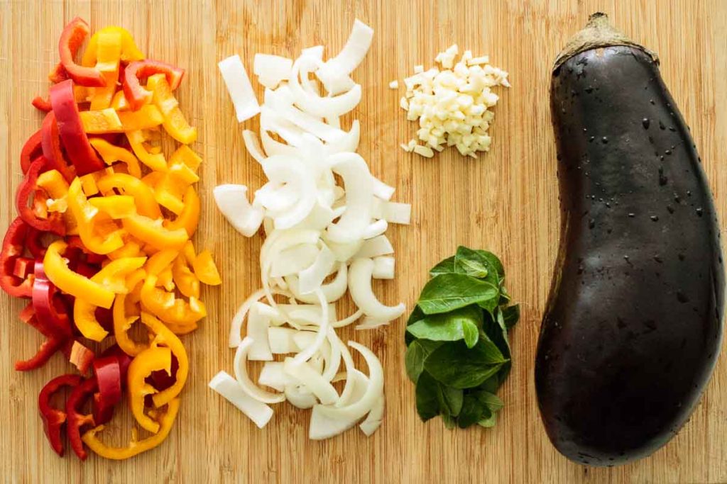 sliced bell peppers, oregano leaves, sliced onion, chopped garlic and an eggplant