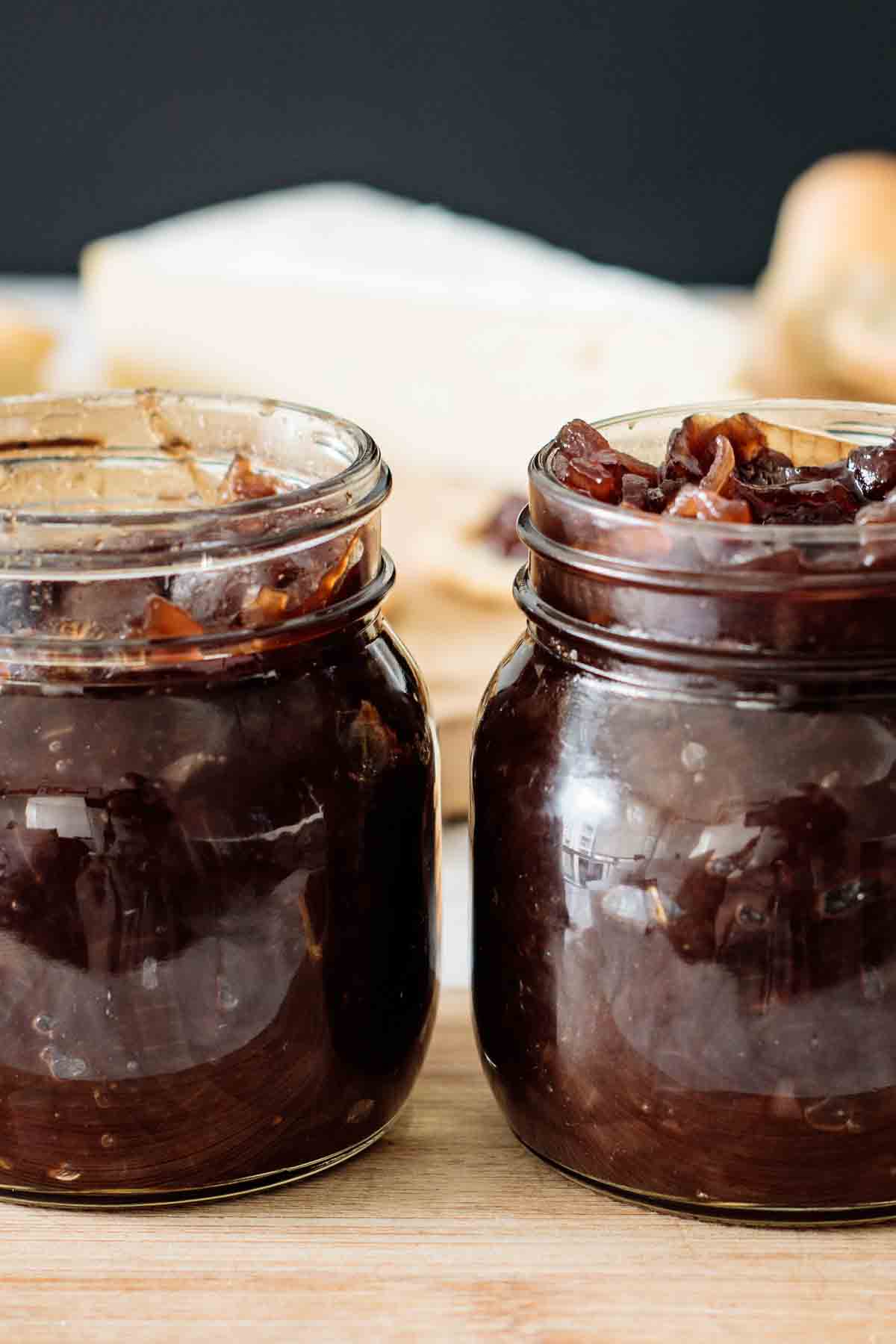 2 jars full of chutney over a wooden board.