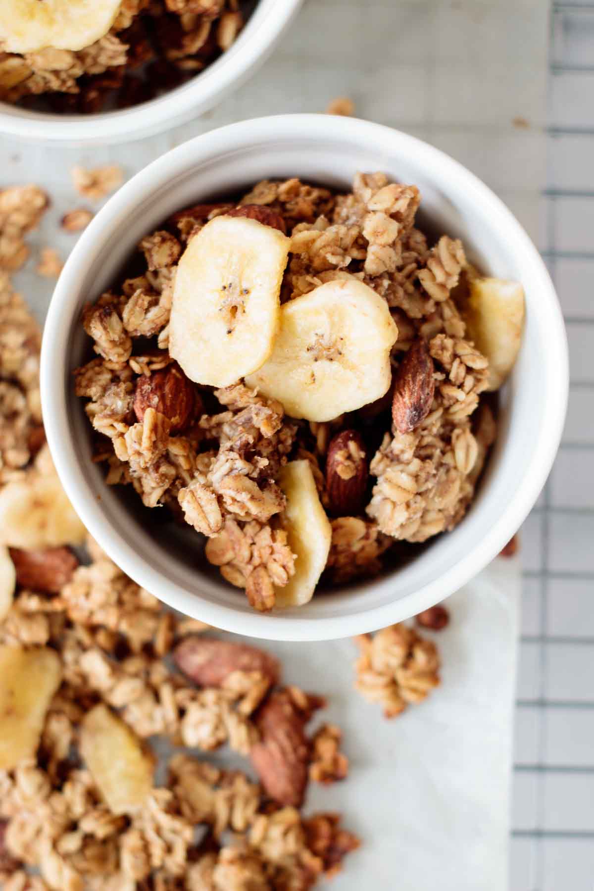 A bowl full of banana bread granola, with granola clusters on the side.