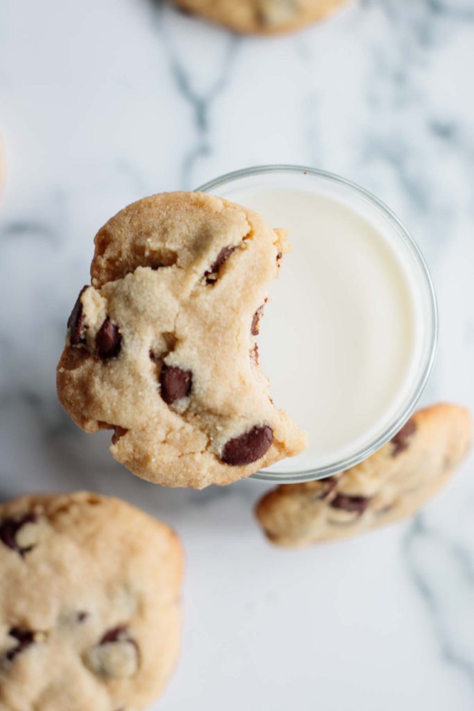chocolate chip cookie half eaten over a glass of milk
