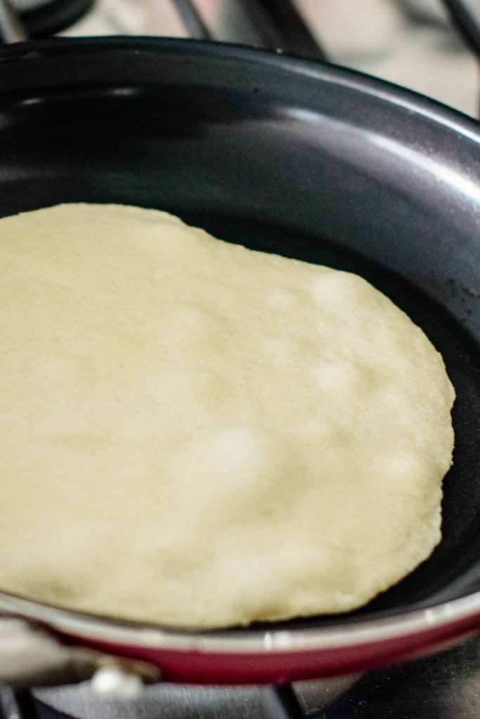 tortilla on frying pan with bubbles and a firm edge