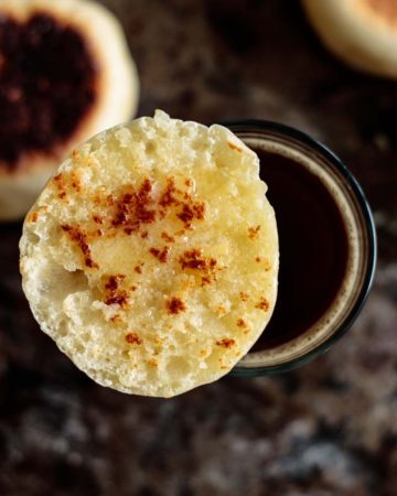 a split and toasted sourdough english muffin over a cup of coffee