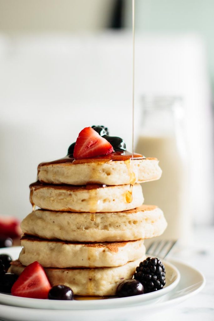 drizzle of maple syrup over stack of pancakes with berries