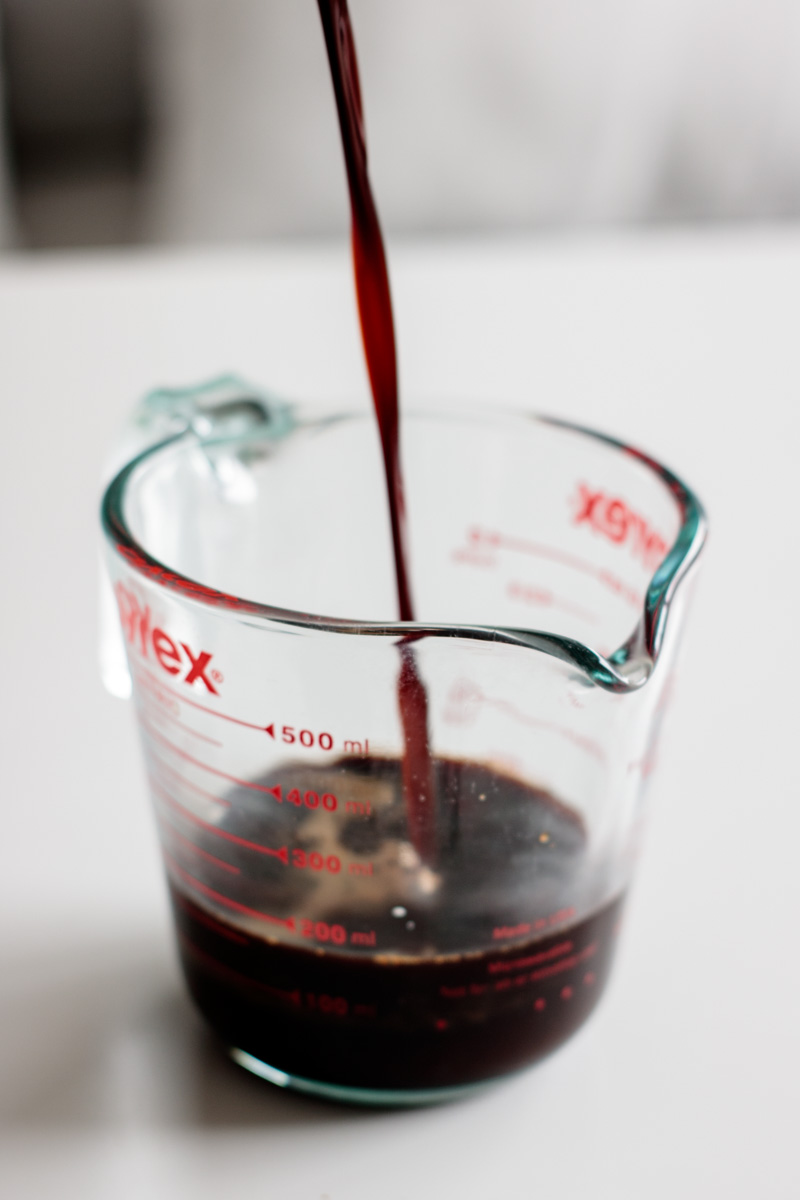 a dark liquid pouring over a transparent measurement jar