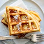A stack of coconut flour waffles, with coconut flakes on the top.