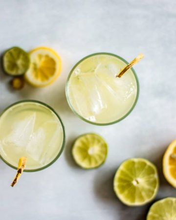 2 glasses of ginger honey iced tea seen from above, with slices of lemon and lime in the background