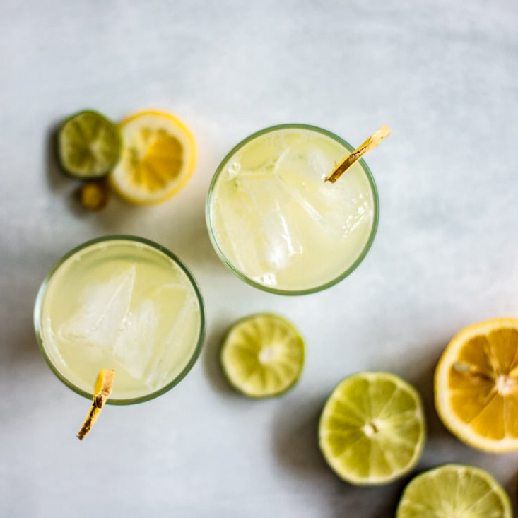 2 glasses of ginger honey iced tea seen from above, with slices of lemon and lime in the background