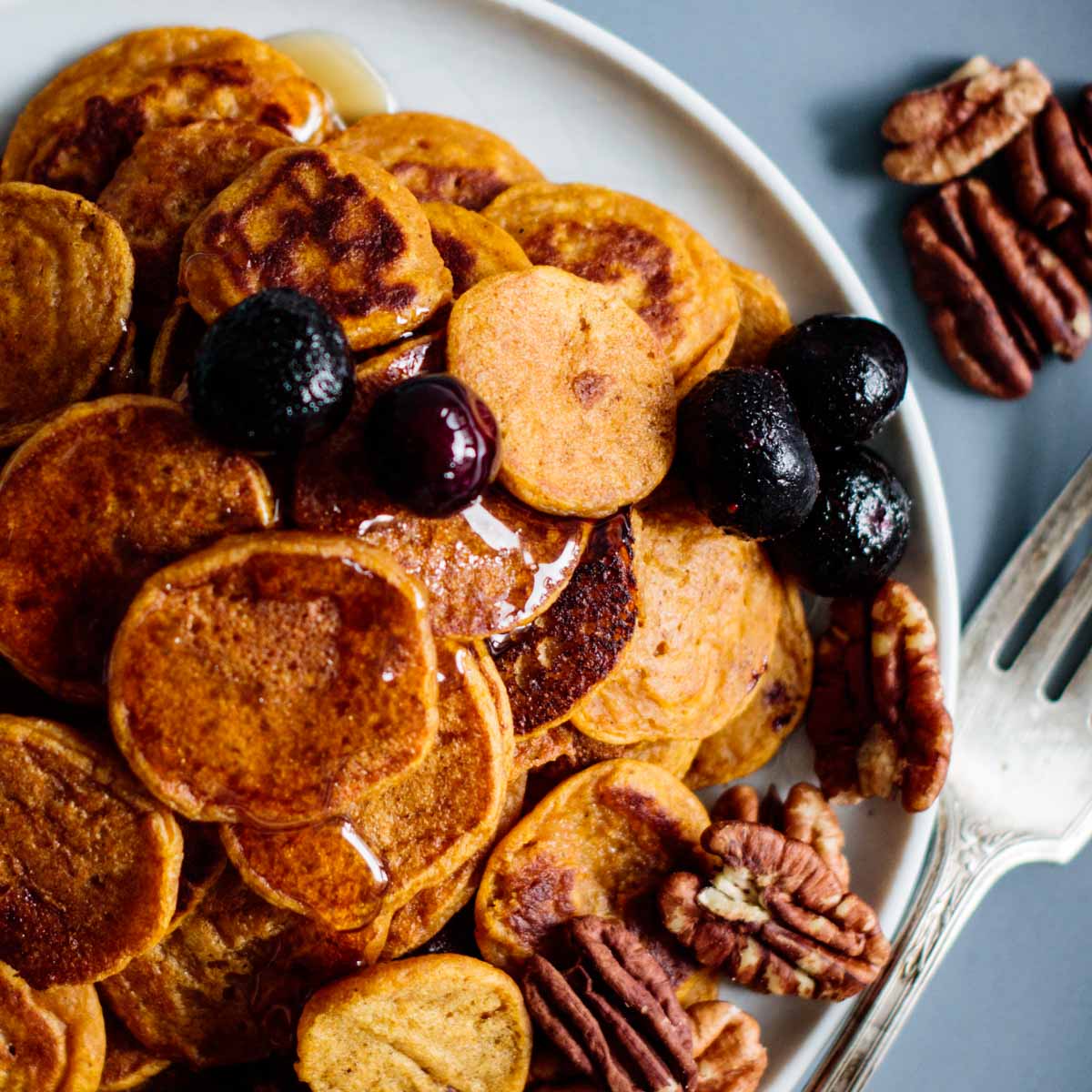 Cereal pancakes with syrup and some granola.