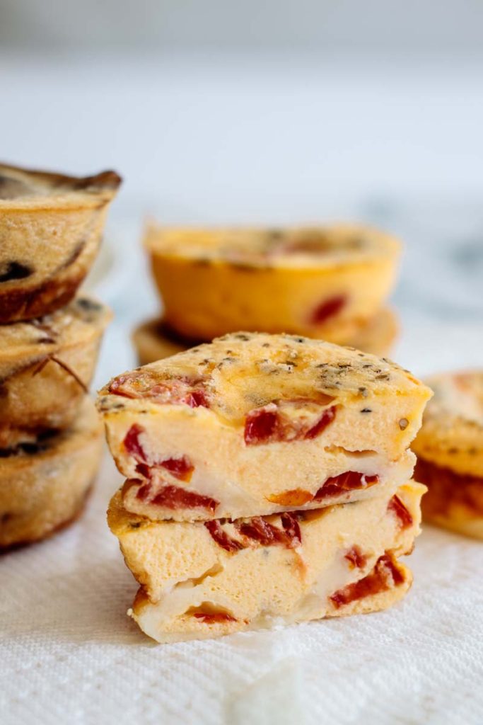 the inside of a breakfast pizza egg muffin cup, showing tomatoes and melted cheese