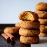 towers of pumpkin snickerdoodles, with two cinnamon sticks on top of a baking sheet