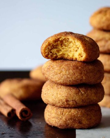 towers of pumpkin snickerdoodles, with two cinnamon sticks on top of a baking sheet