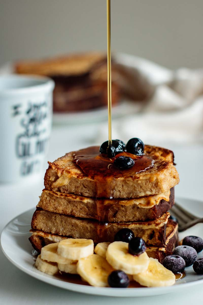 maple syrup drizzling on top of a sourdough french toast stack