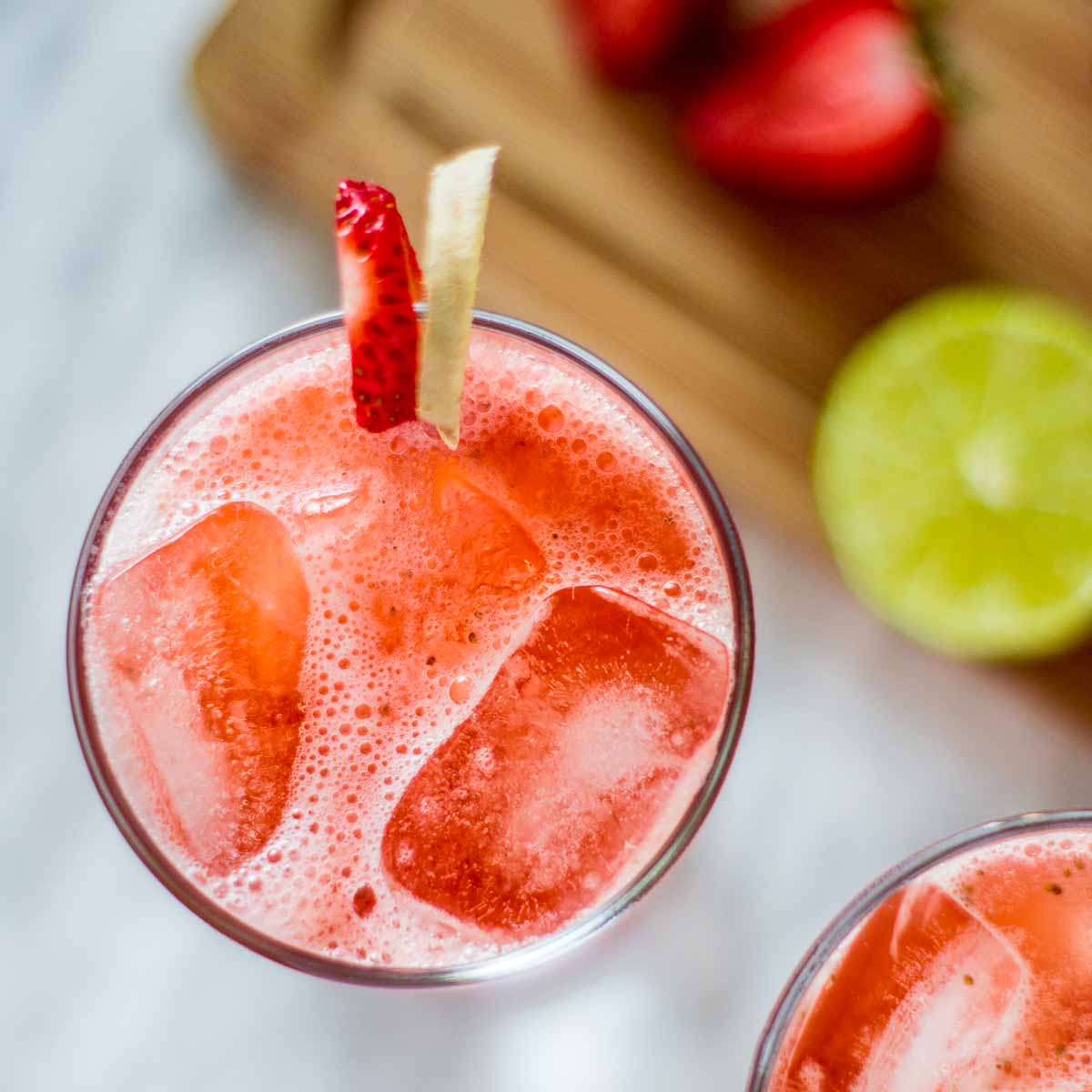  de cerca en un vaso de jugo de fresa con cubitos de hielo y guarnición