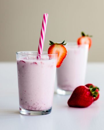 korean strawberry milk on a decorated glass with pink straw and strawberry on the side