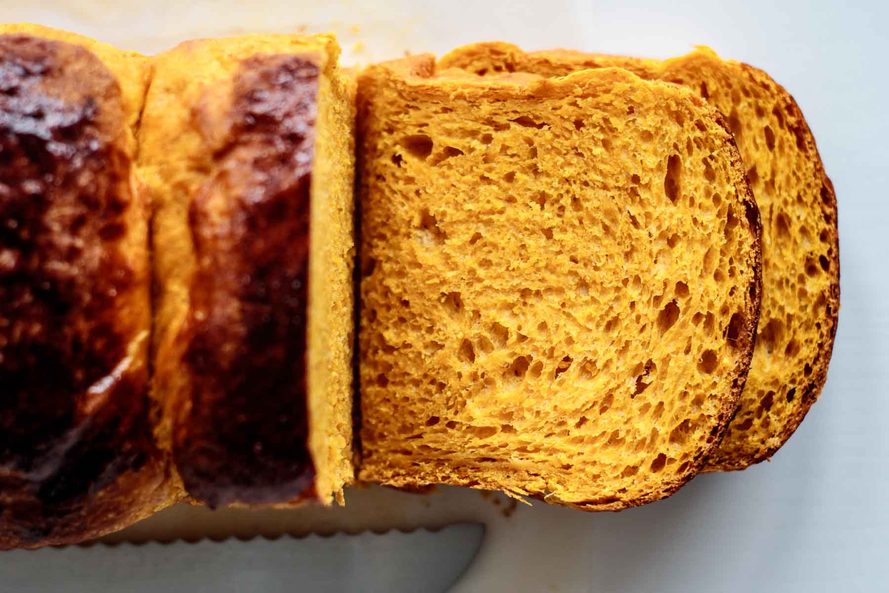 close up on sliced pumpkin brioche, showing its soft and bright orange crumb