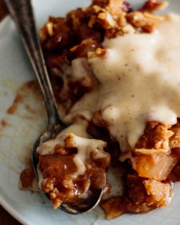 apple crisp with eggnog sauce in a plate with spoon