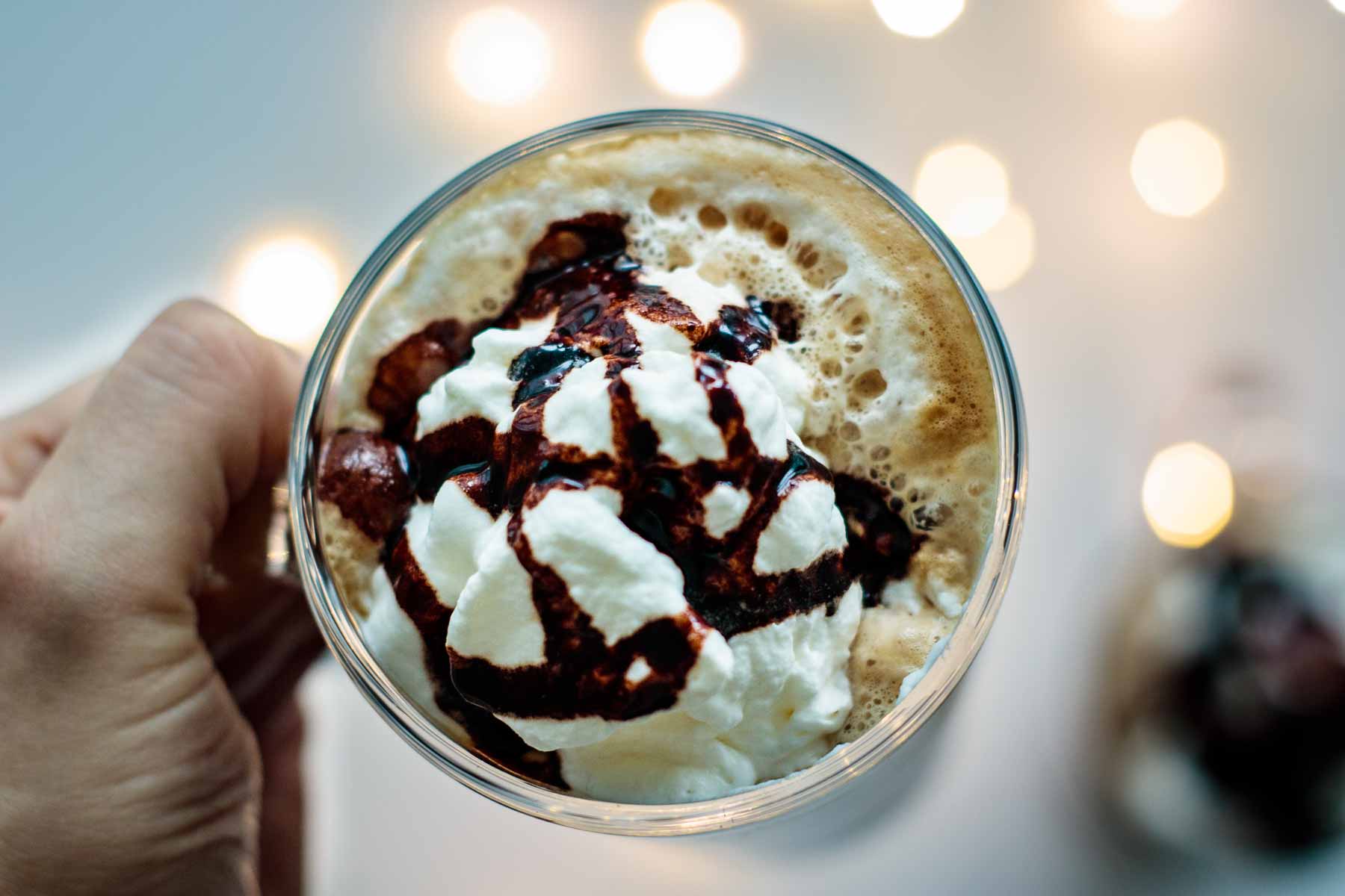 beverage in a glass cup seen from above, with mocha sauce and whipped cream on top