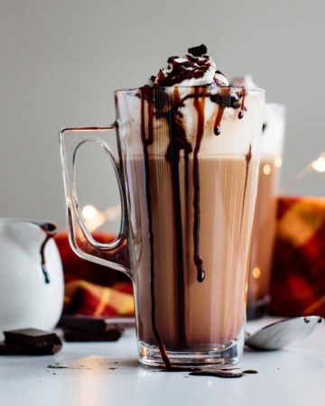 mocha latte ready, with chocolate, mocha sauce and spoon on the background