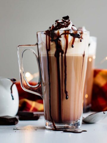 mocha latte ready, with chocolate, mocha sauce and spoon on the background