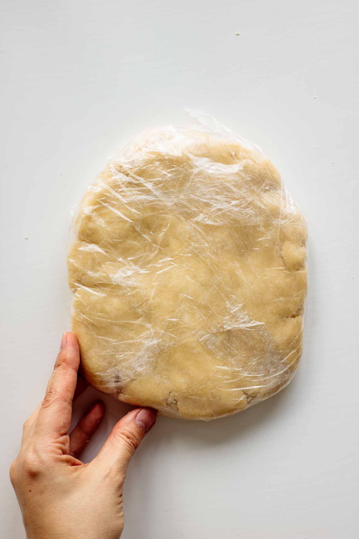 Sourdough discard pie crust dough covered in plastic wrap.