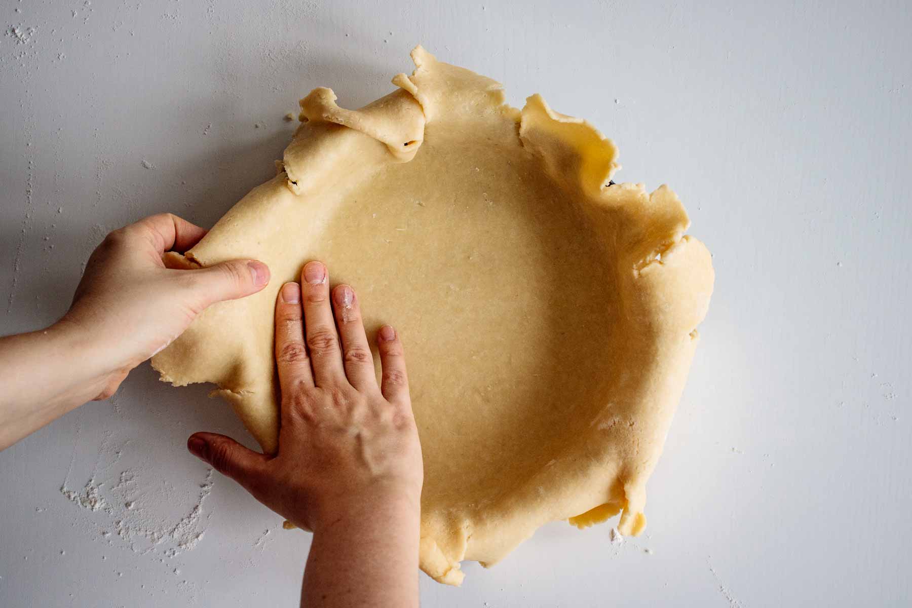 Dough being placed gently in a blue pie dish.