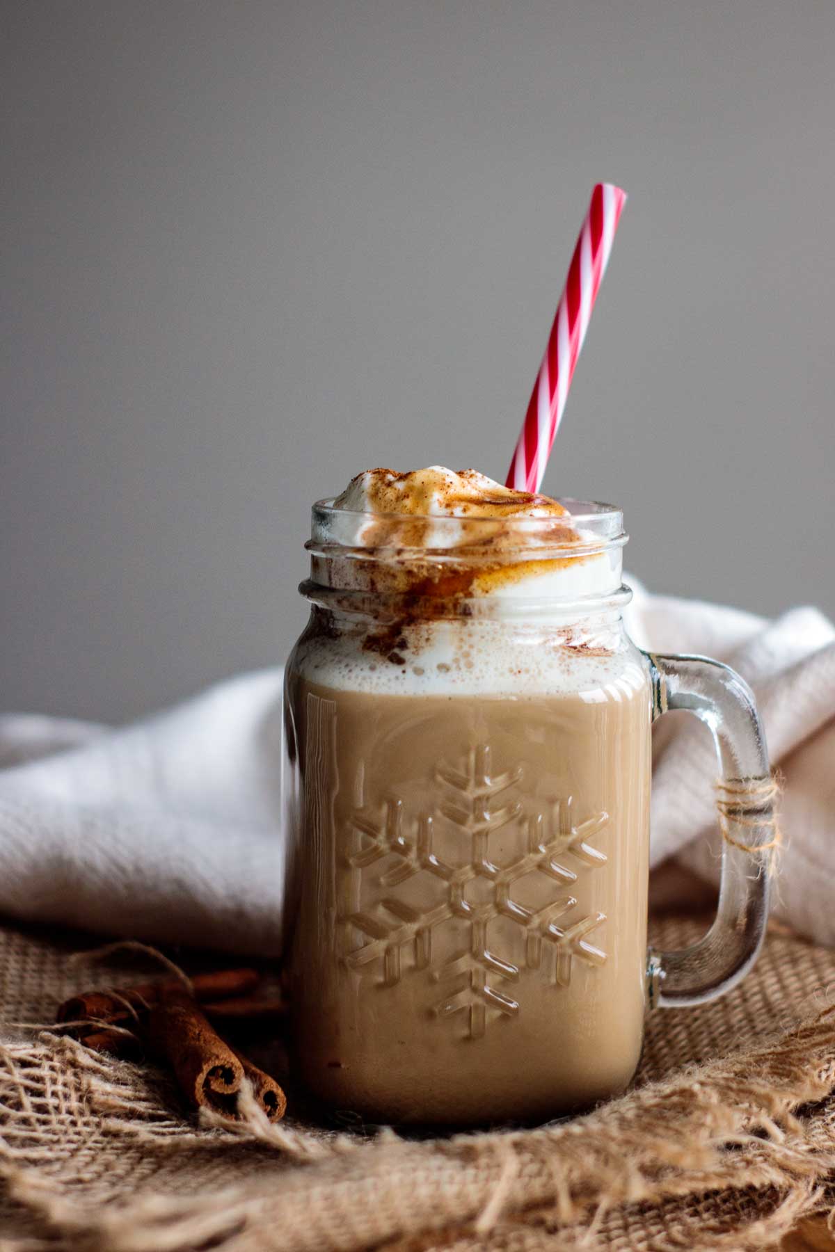 starbucks copycat of the famous cinnamon dolce latte, with a red reusable straw and cinnamon syrup topping the whipped cream