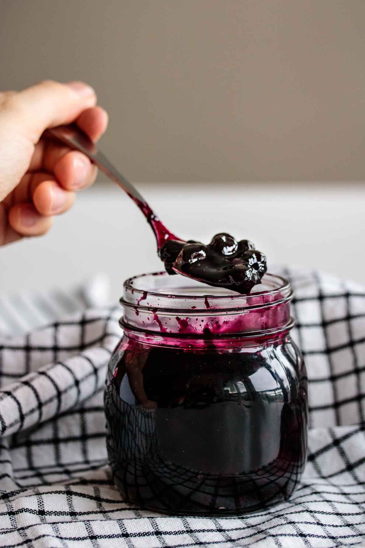 a hand holding a spoon full of compote