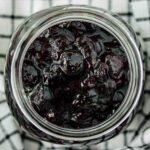 close up of a jar of blueberry compote over a kitchen towel