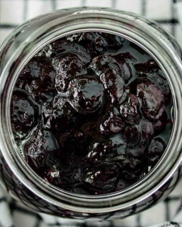 close up of a jar of blueberry compote over a kitchen towel