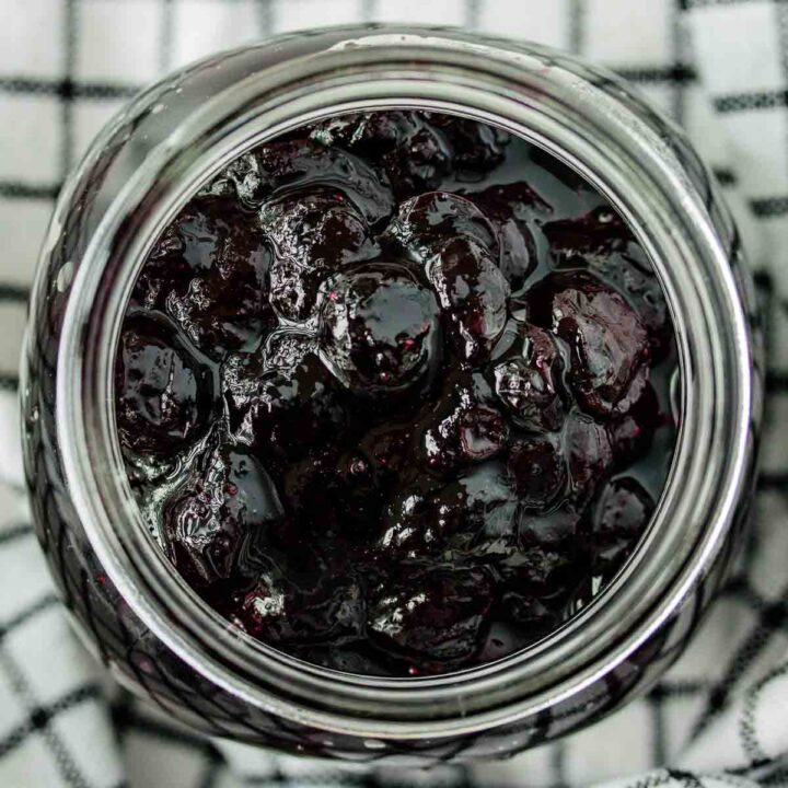 close up of a jar of blueberry compote over a kitchen towel