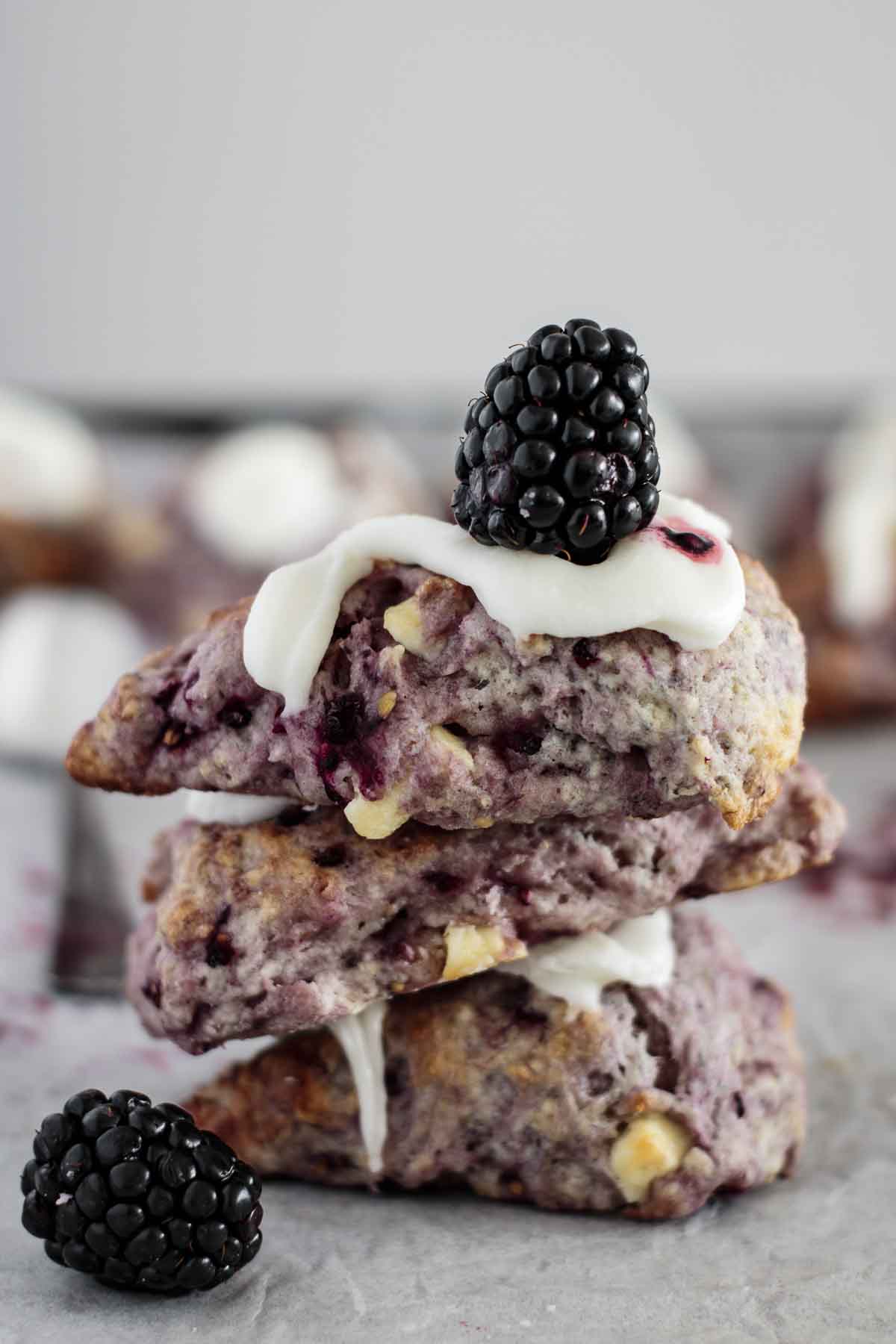 Three scones piled over each other, with lime glaze and a berry on top.