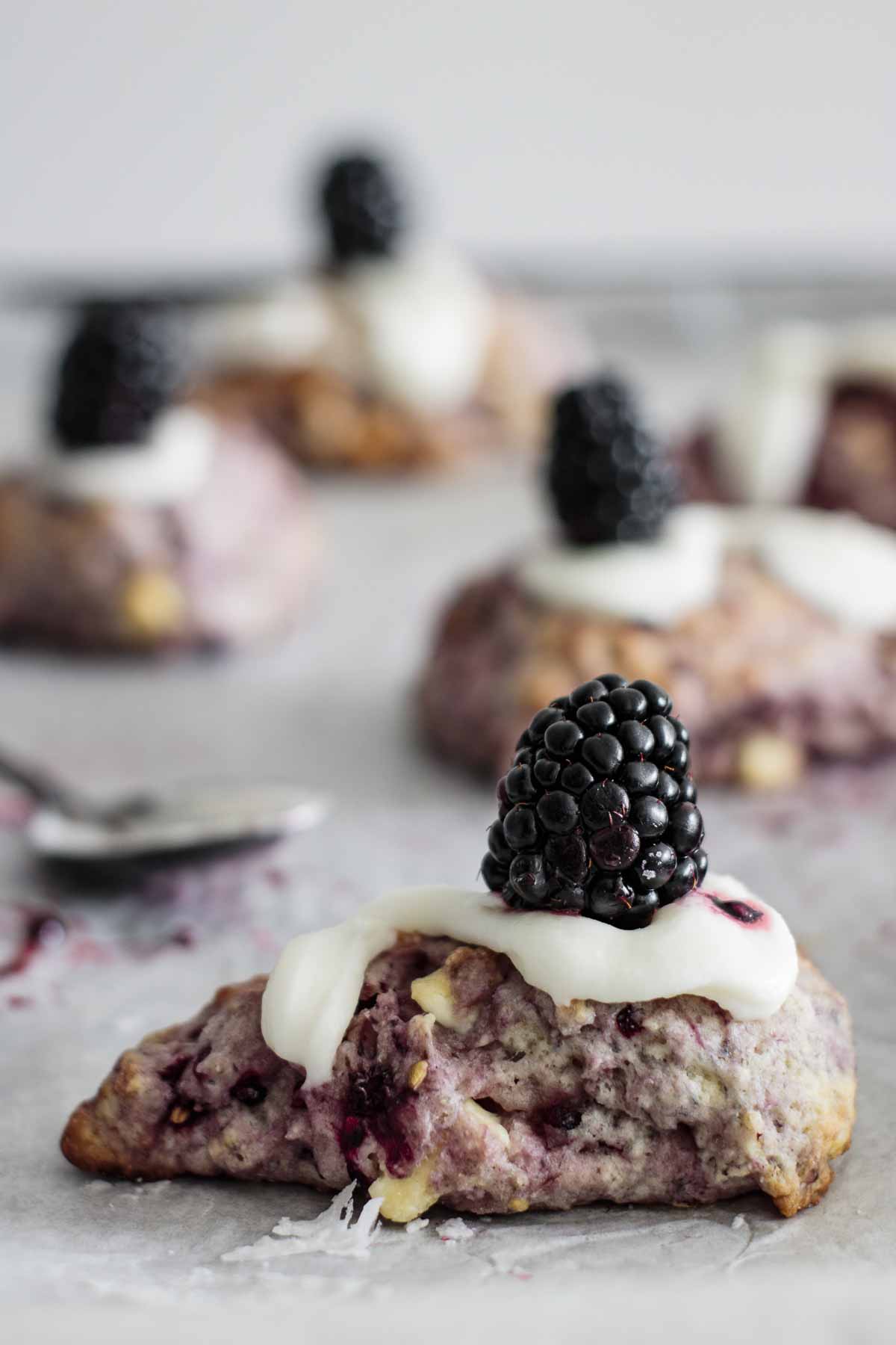 Blackberry scone with glaze and a fresh blackberry on top.