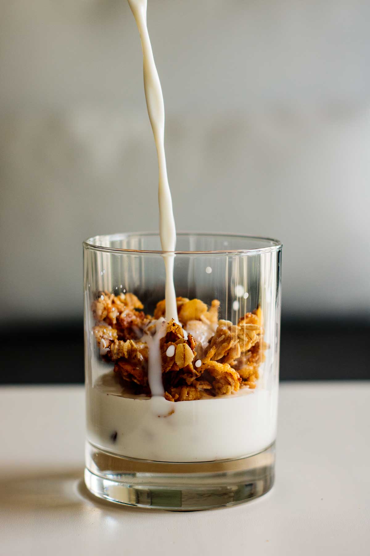 milk pouring over a glass with granola