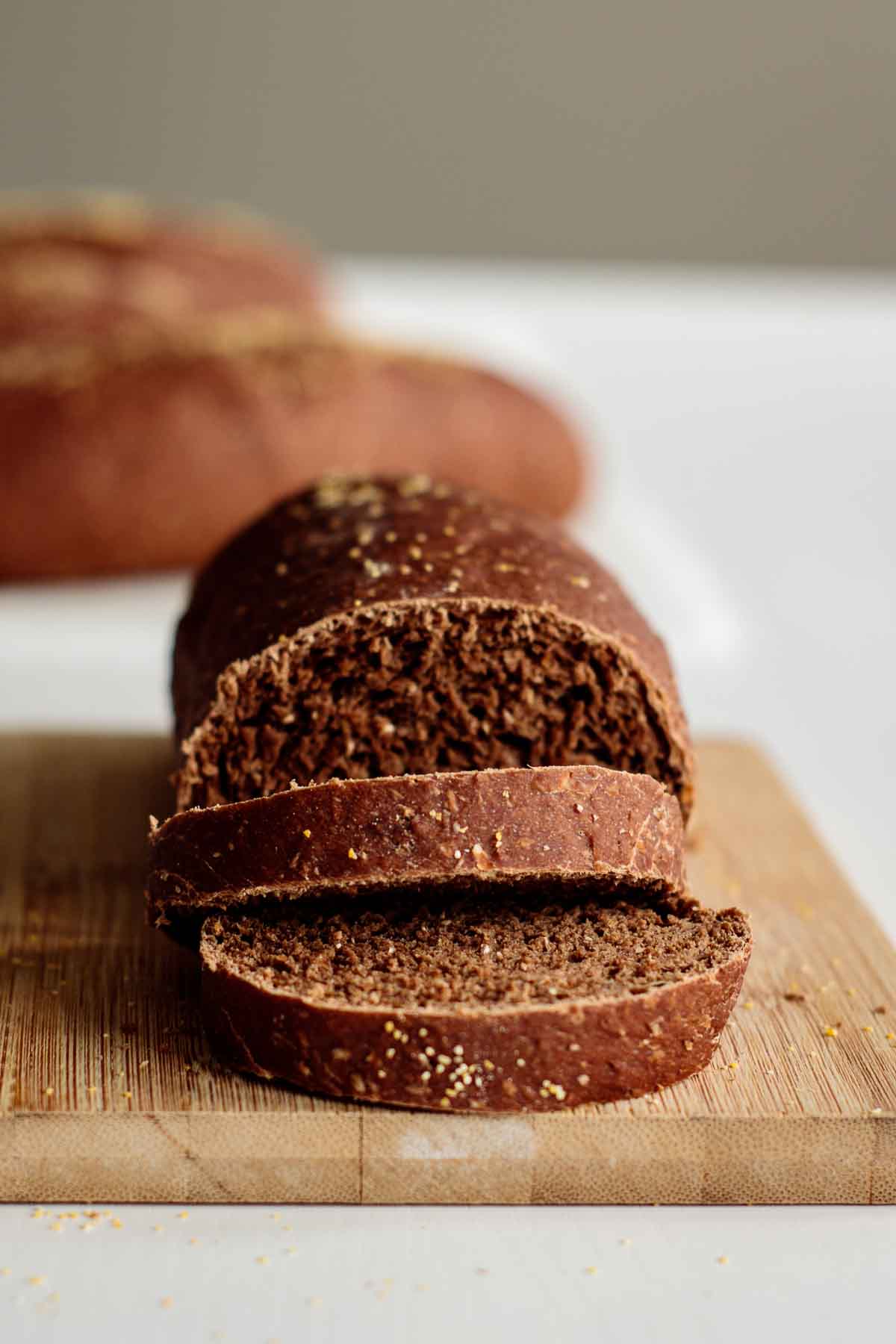 Loaf sliced on the top of a wooden board with outback bread rolls in the background.