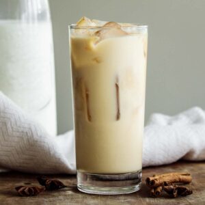 Iced chai tea latte in a tall glass over ice cubes.