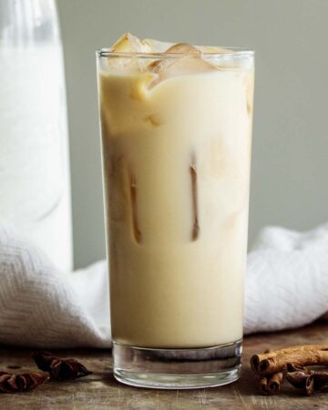 Iced chai tea latte in a tall glass over ice cubes.