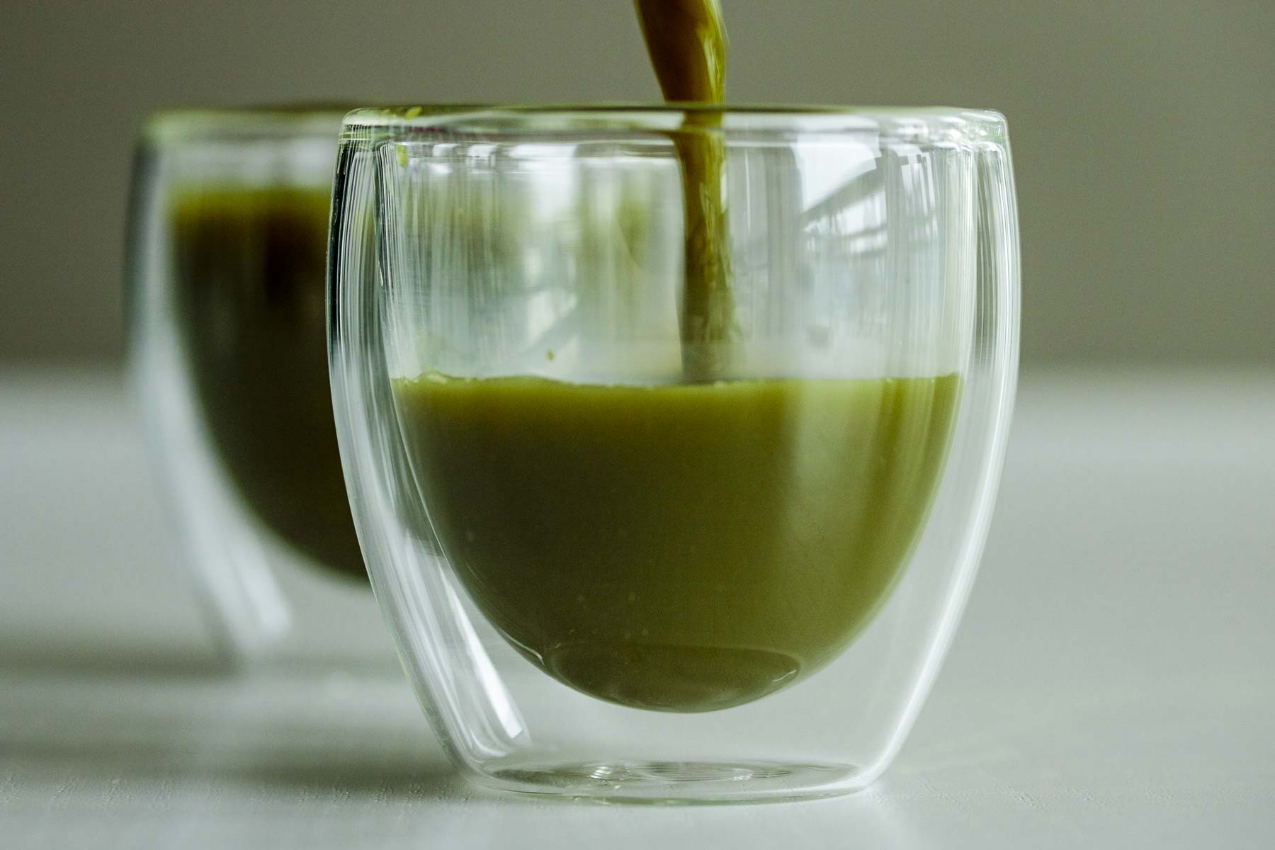 Pouring Macha tea in a transparent glass.