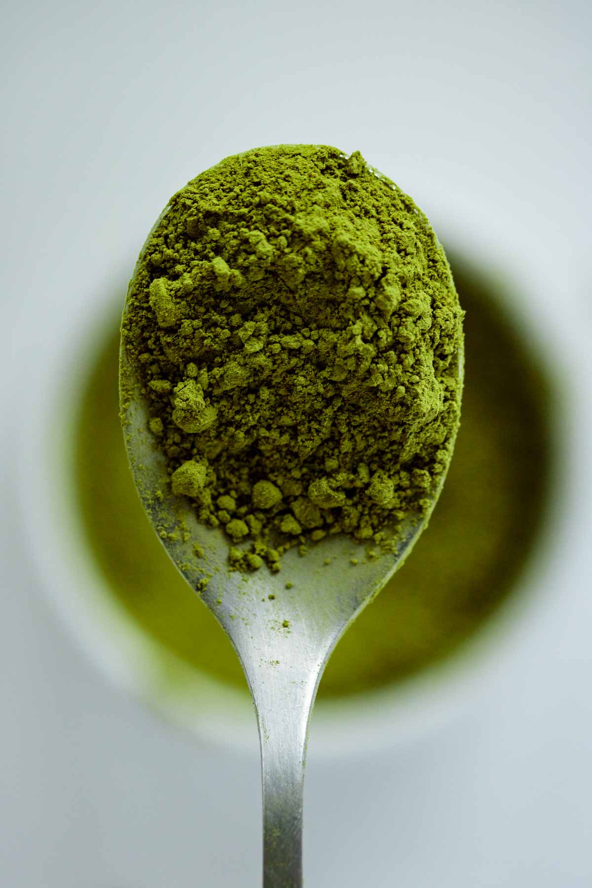 Close up on a spoon filled with vibrant green Matcha powder.