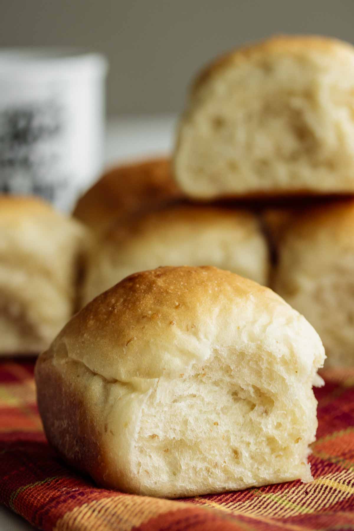 close up on sourdough dinner roll with more rolls on the back.