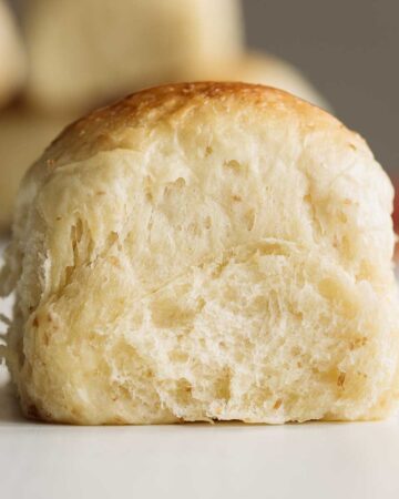 Close up on sourdough dinner roll, showing its soft crumb.