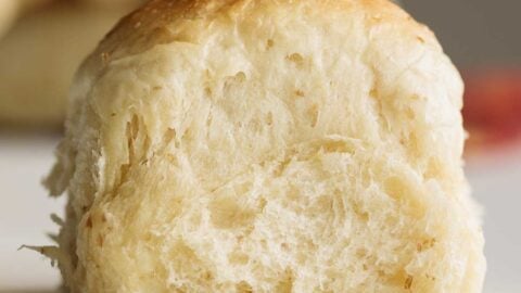 Close up on sourdough dinner roll, showing its soft crumb.