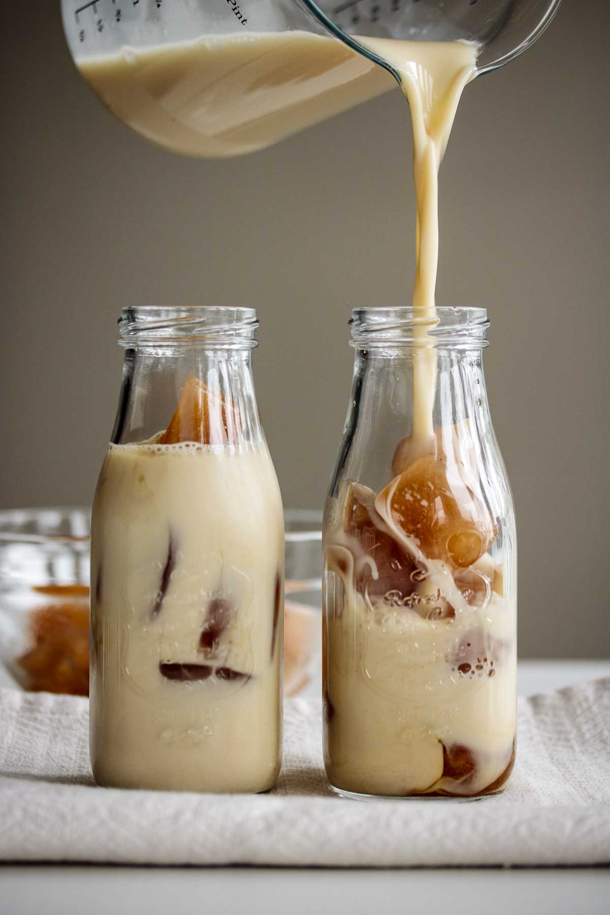 Cold brew milk tea pouring over ice cubes.